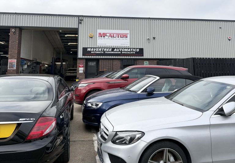 MC Autos garage in Croydon. It's a corrugated steel building with the sign on it, and there are 4 cars outside.